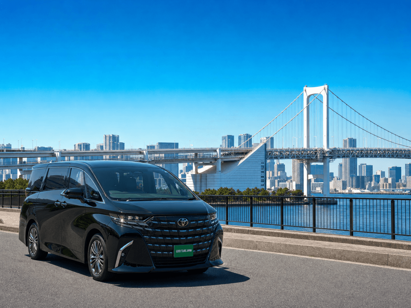Black Toyota minivan parked on a road overlooking Tokyo's Rainbow Bridge and city skyline.
